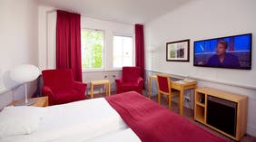 Large twin room with TV and desk at Bolinder Munktell Hotel in Eskilstuna