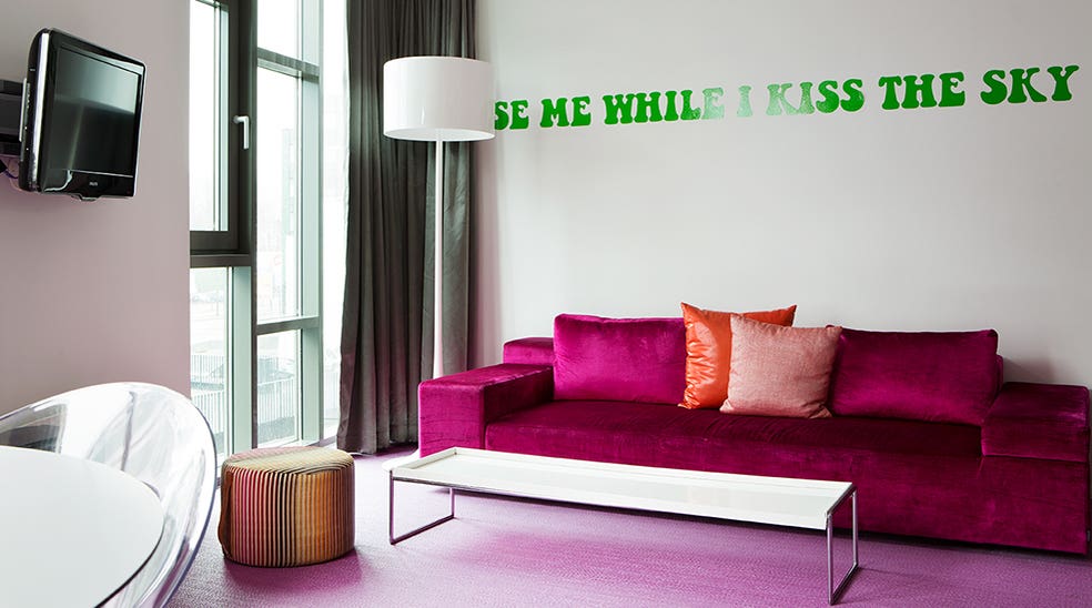 Flowerpower suite with pink sofa and green Jimi Hendrix quote on the wall at Comfort Hotel Union Brygge in Drammen in Norway