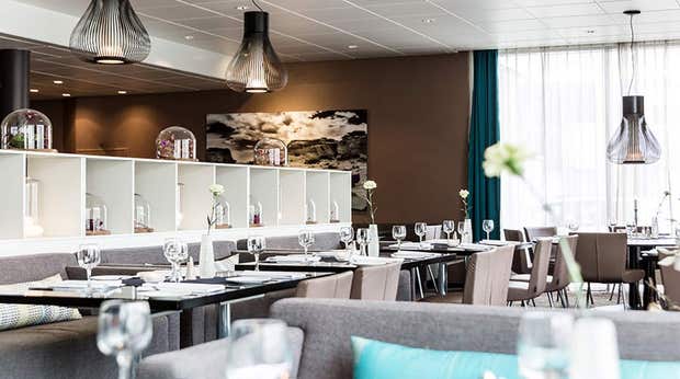 Dining area with a sofa, chairs and set table with wine glasses in the restaurant at the Quality Airport Hotel Værnes