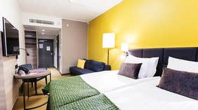 Superior double room with a double bed, soda, yellow walls and a seating area at the Quality Hotel Winn Haninge